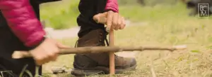 Woman Rubbing Sticks Together to Make Fire