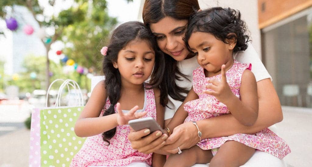 Mother with two daughters watching something on moms phone
